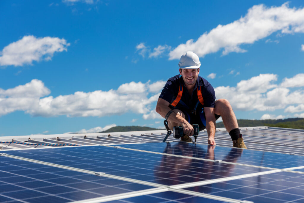 Solar panel technician with drill installing solar panels