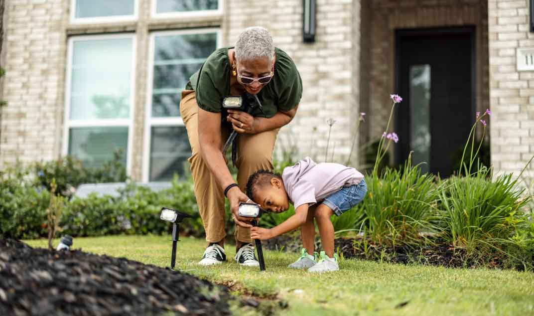Grandmother and grandson installing solar lights in yard